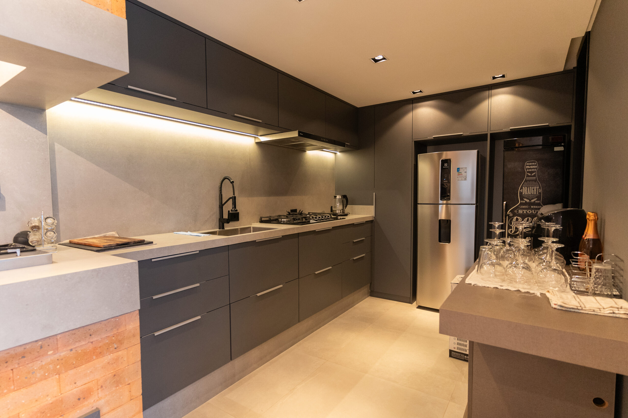 Cozinha planejada com iluminação embutida em perfil de LED destacando a bancada e os armários.