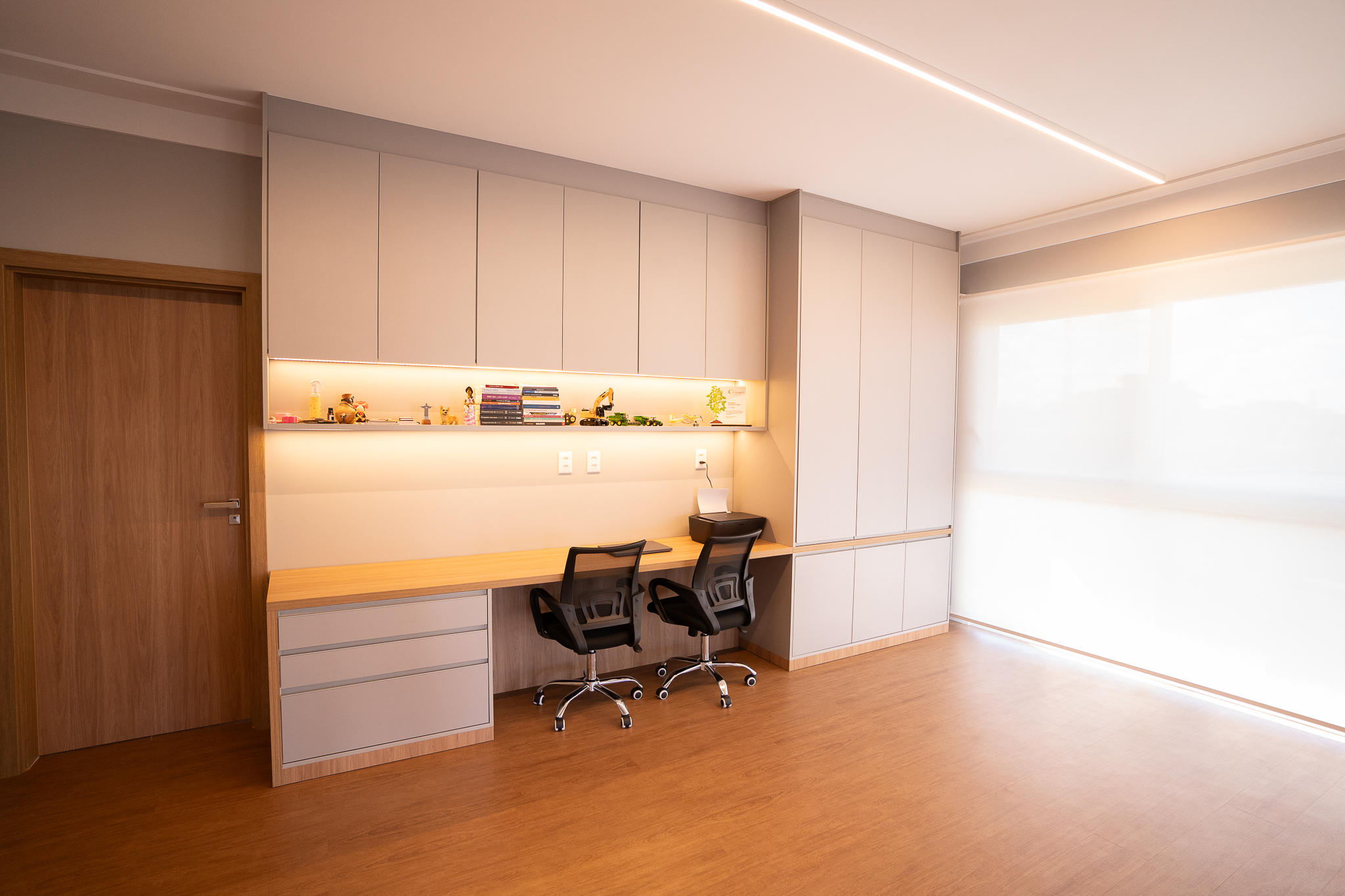 Home office planejado com bancada sob medida e prateleiras organizadas.