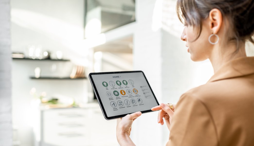 Mulher controlando dispositivos domésticos inteligentes usando um tablet digital com aplicativo lançado na sala de estar